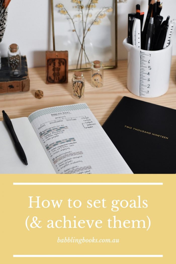 Graphic with image of journals and some vintage items on a desk. White text on a yellow background at the bottom says 'How to set goals (and achieve them)'