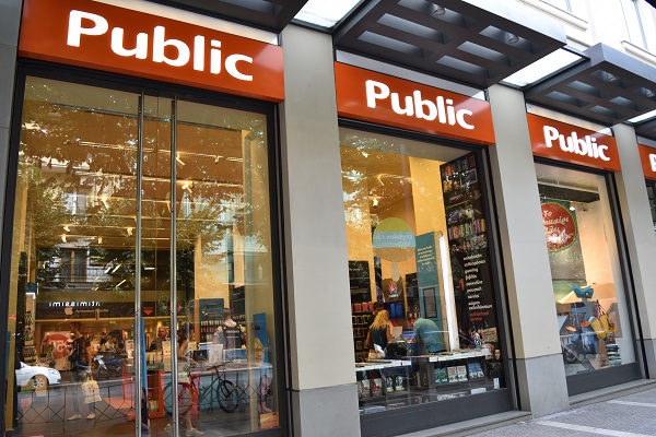 Front of Public store in Tsimiski. Large glass windows with an orange sign above and bookshelves visible inside.