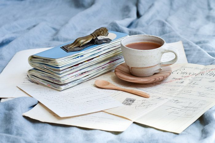 Creative journal ideas and inspiration, featuring a stack of journals, antique hand written letters and a cup of tea