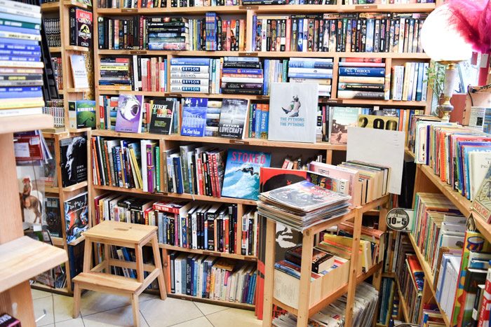 Interior of Elephant Books, bookstore in Sofia, Bulgaria. Wooden bookshelves are filled with neatly stacked books and a small wooden stepping stool is in front of the shelves.