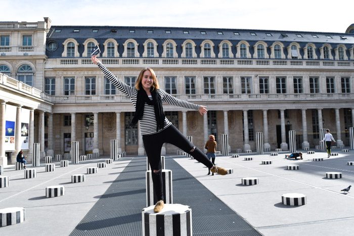 Tamsien standing on a black and white pole outside Palais Royale in Paris