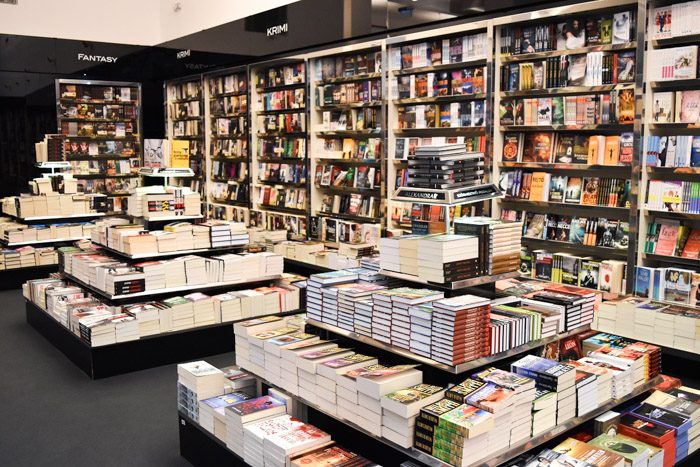 Black and white bookshelves and floor displays filled with books focused on fantasy and crime.