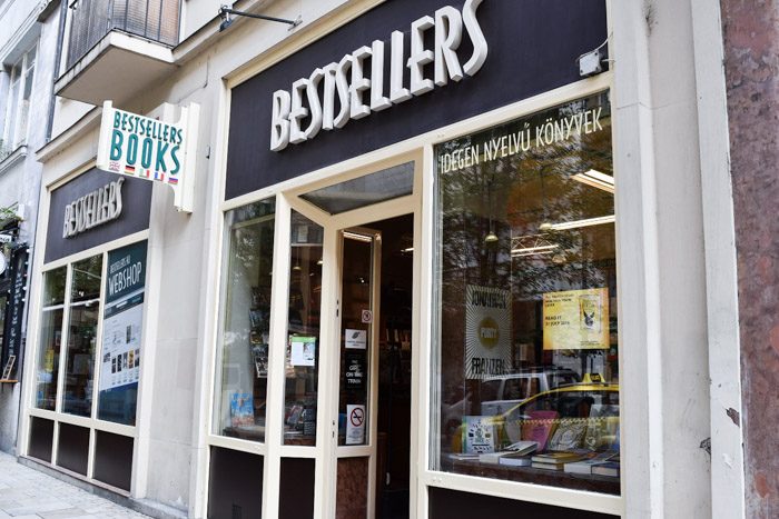 Angled photo of the front of Bestsellers displaying a white trim shopfront and windows that display the inside of the bookshop.