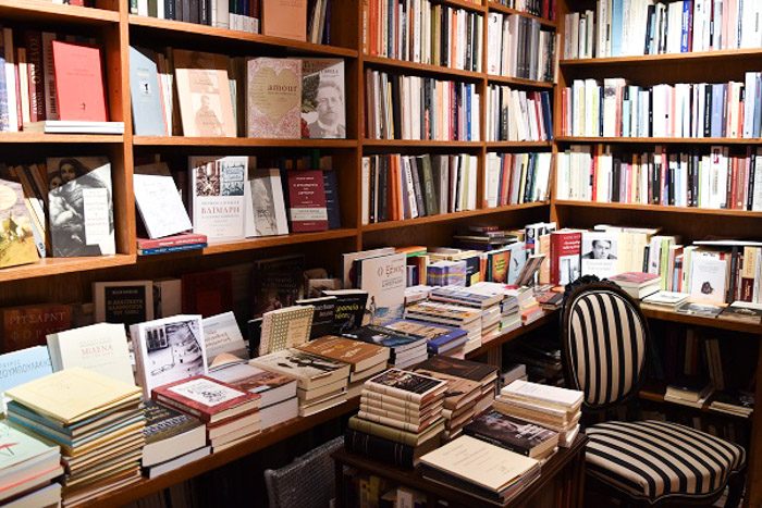 Wooden bookshelves are filled with books, and a small black and white striped chair is visible in the right corner.