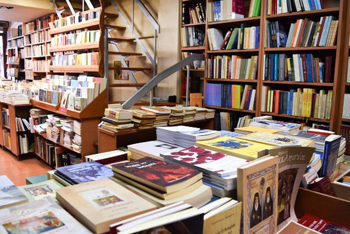 Inside Nautilus Bookstore, Athens, Greece.  Books on wooden shelves line every surface, and a staircase disappears out of sight.