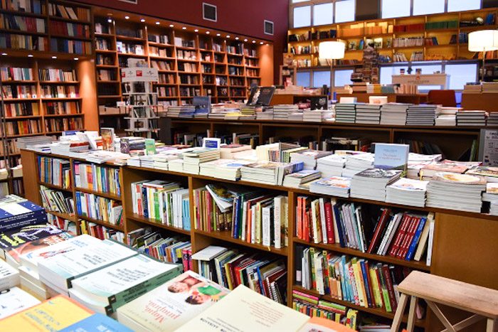 Inside Pataki Bookstore, Athens. Orderly rows of books on wooden shelving fill the room.