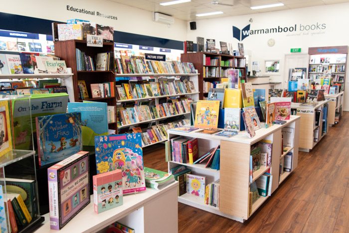 Picture of a long row of shelves from another angle, showing educational books as well as children's books.