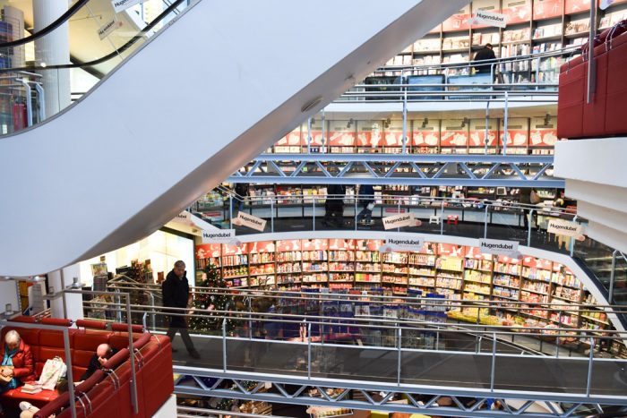 Curved wall across multiple internal floors containing a huge range of books for sale.