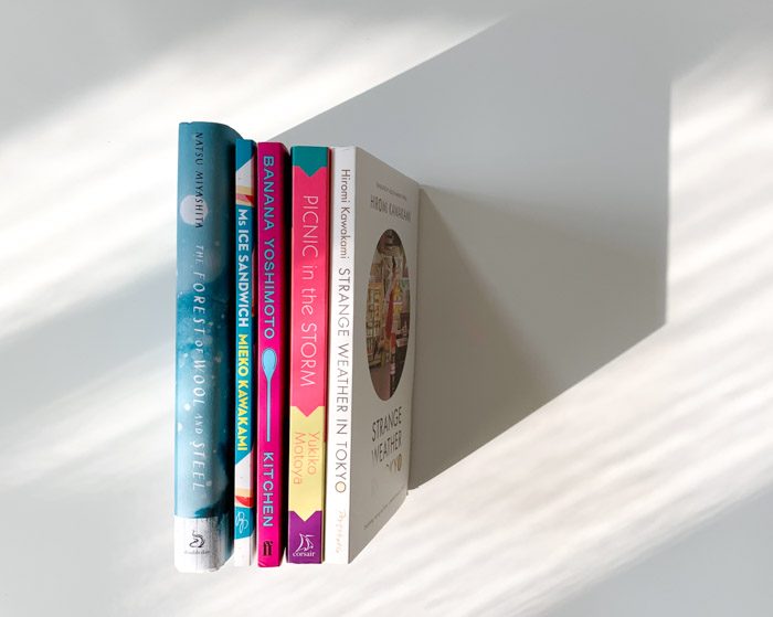 Five books arranged with spines facing up on a white flat background