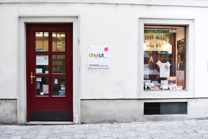 The white shopfront of ChickLit with red door and one large rectangular window.