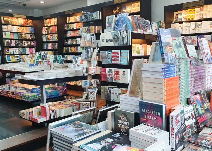 Interior of Periplus Bookshop. Books are neatly stacked on wooden shelves and tables.