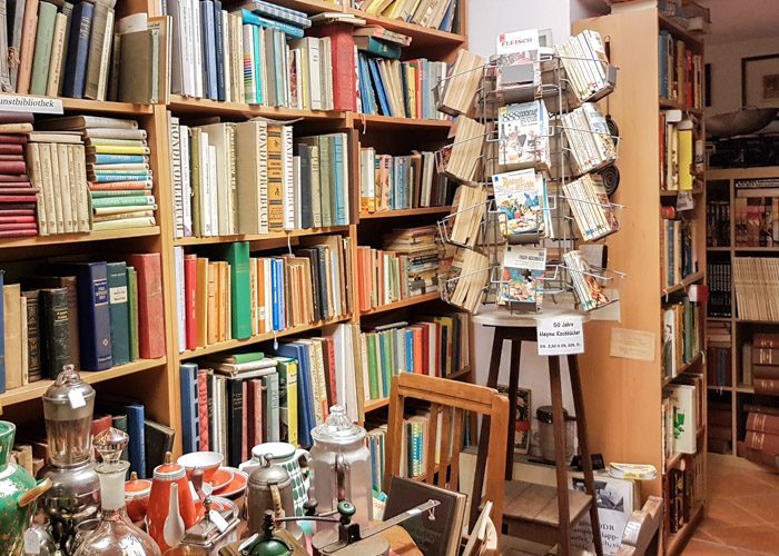 One corner of this bookstore filled with a large range of secondhand books stacked on bookshelves and a tea set on a table.