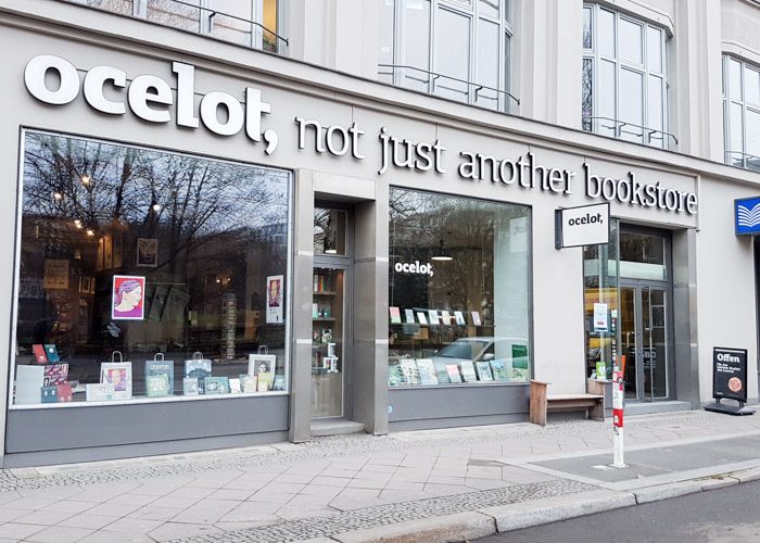 Stone grey shop front of Ocelot bookstore with large square windows.