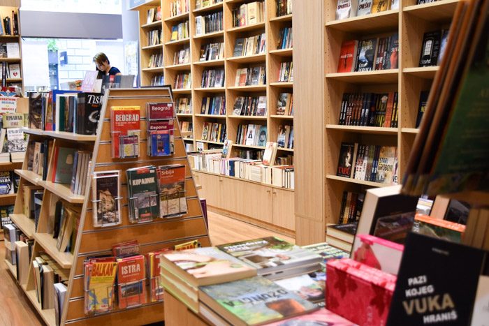 Interior of Delfi Laguna. Pale wooden shelves hold a variety of books. Book Lover's Guide to Belgrade, Serbia.