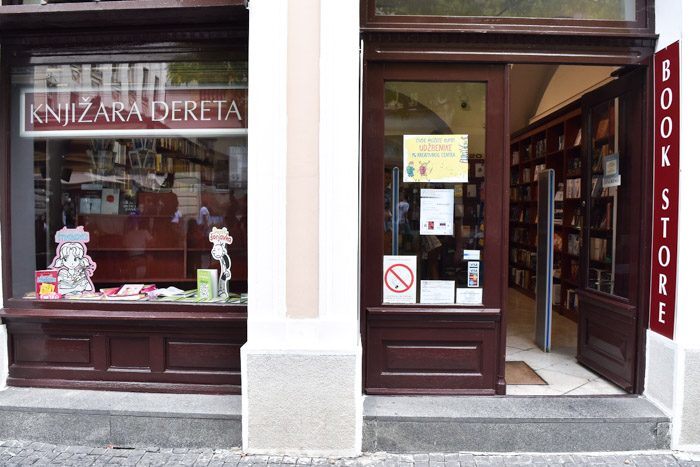 Exterior of Derta Bookstore. Dark red painted doors and window frames reveal hints of bookshelves inside. Book Lover's Guide to Belgrade, Serbia.