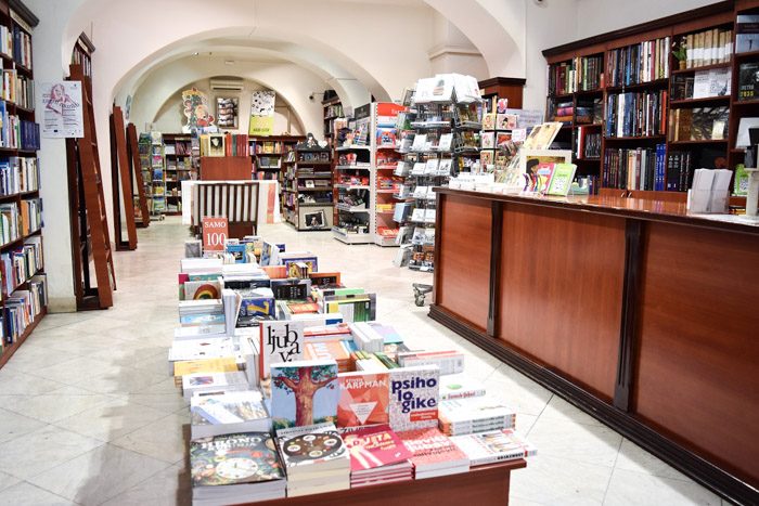 Interior of Derta Bookstore. Wooden shelves with ladders line a long room with curved ceiling and arches. Book Lover's Guide to Belgrade, Serbia.