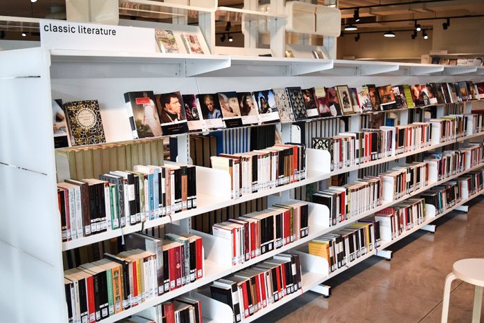 Geelong Library interior, long white shelves are stacked neatly with books. A sign read 'classic literature'.