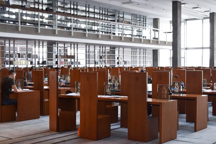 Interior of the National Library of Serbia. Wooden chairs and tables are neatly arranged in a light reading area. Book Lover's Guide to Belgrade, Serbia.