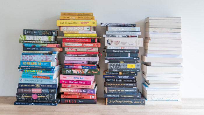 Four stacks of books, arranged by colour. The far right column has books stacked with their pages facing forward